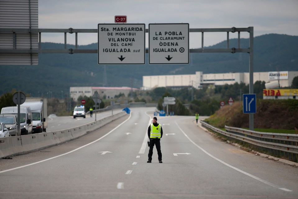  A mosso de esquadra police officer stands on a closed off road near Igualada, Spain