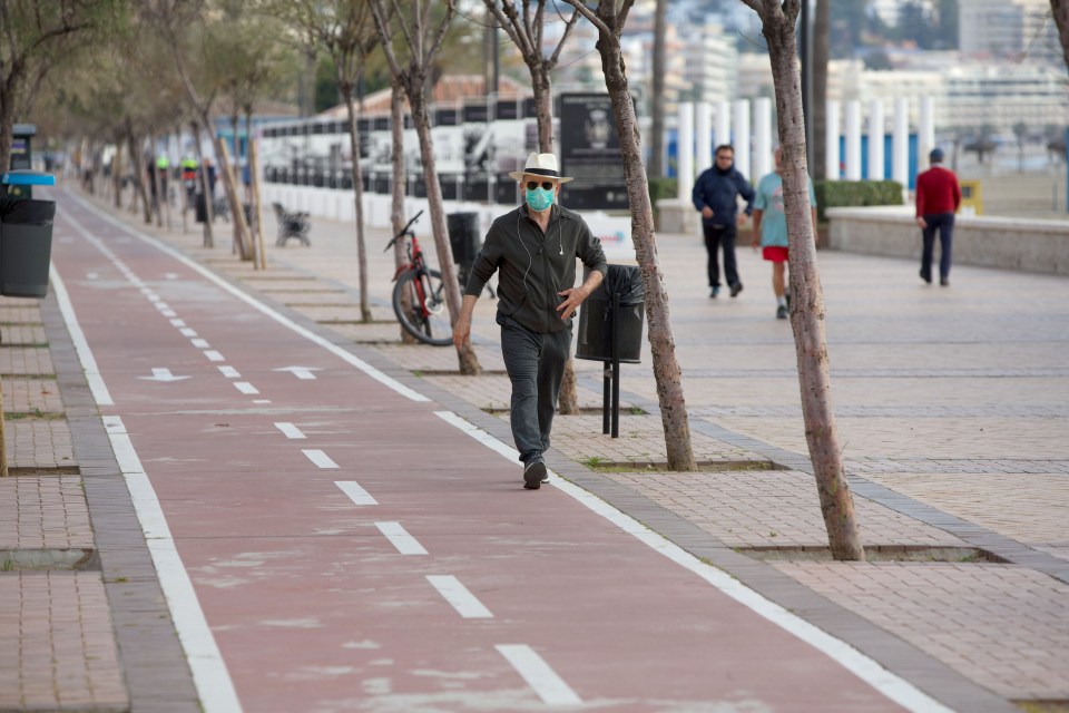  A man in a face mask walks along a path near the Fuengirola Beaches amid the shut down