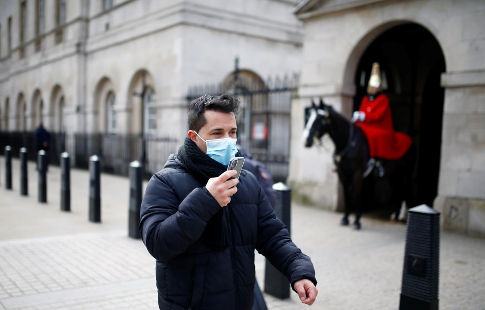  A man wearing protective mask walks past the Horse Guards in London