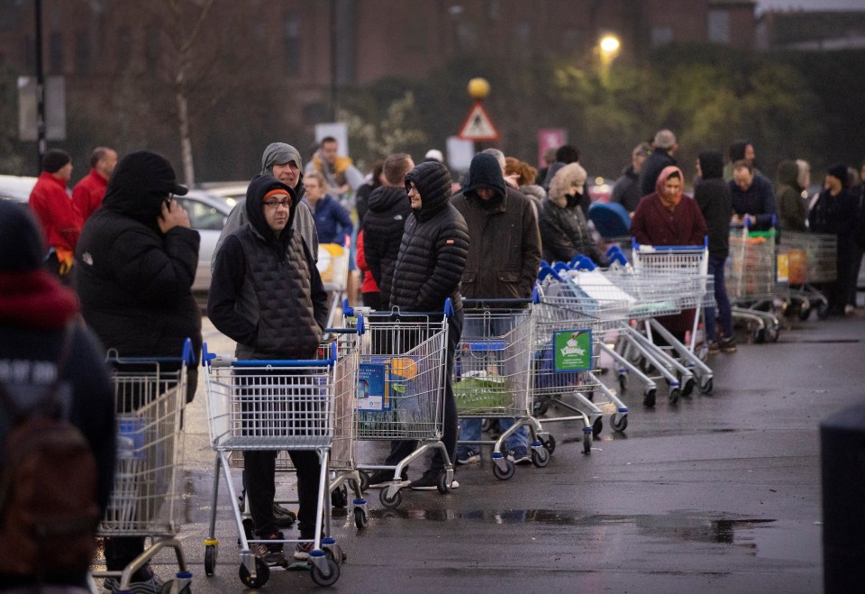 Shoppers line up in the car park of a Tesco Extra store in New Malden, South London, at 6am today