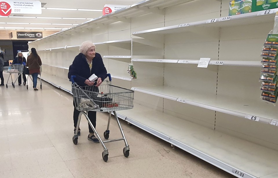 A poignant image shows an elderly woman staring at empty shelves in a Tesco supermarket in Kent just at 7am this morning