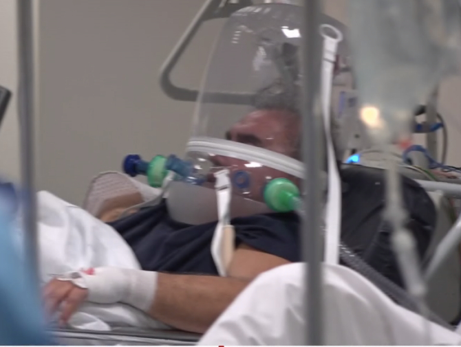  A man can be seen in a bubble helmet being treated in Lombardy