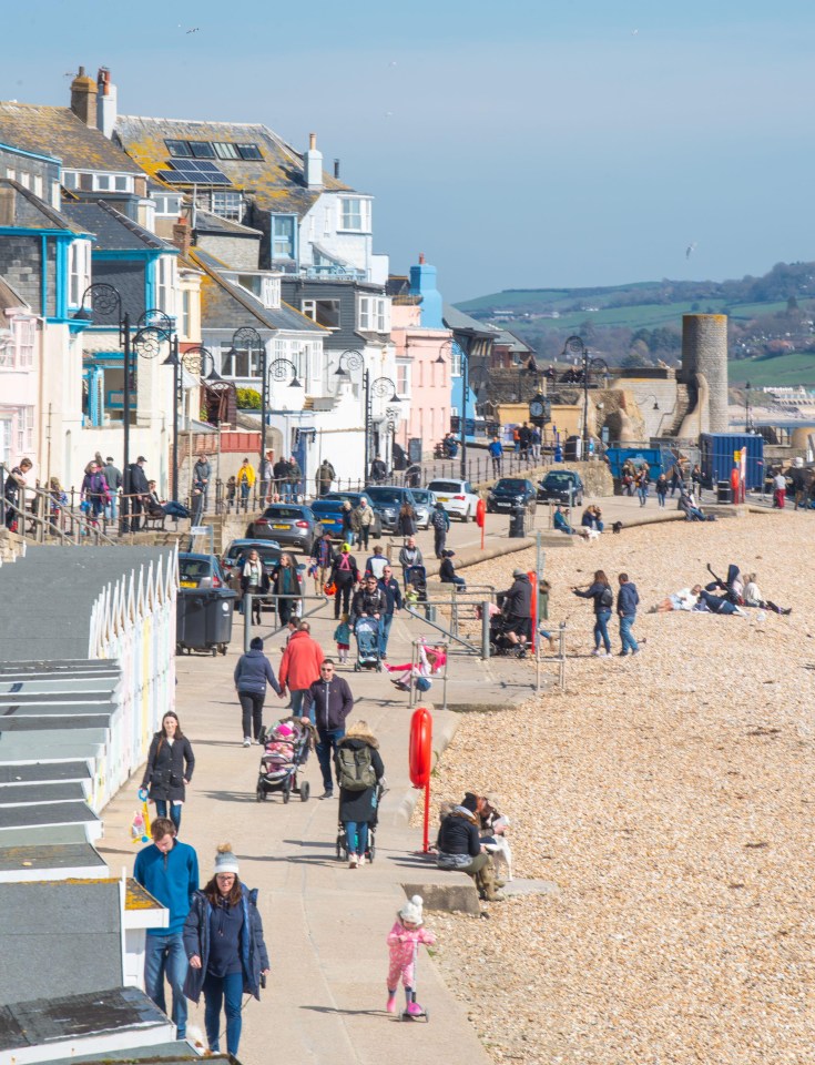 Families stroll along the beach at Lyme Regis on a beautiful sunny Mother’s Day