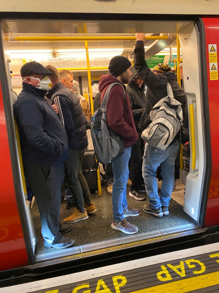  Passengers wearing masks cram onto a Tube train on the District line