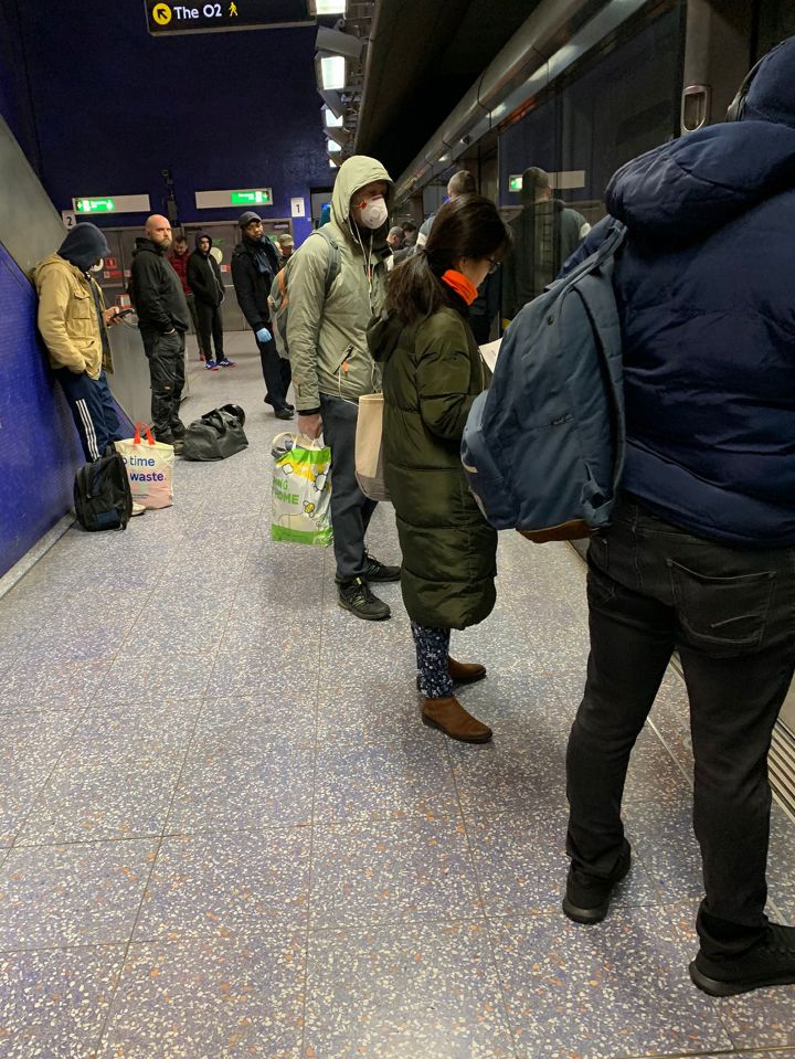  A commuter wearing a mask queues to get on the Tube in rush hour this morning at North Greenwich station