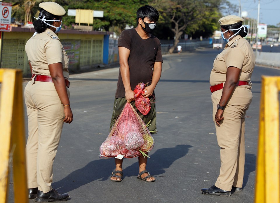 A man carrying vegetables is stopped by police at a barricade on a road during a 21-day nationwide lockdown to limit the spreading of coronavirus disease (COVID-19) in Chennai, India