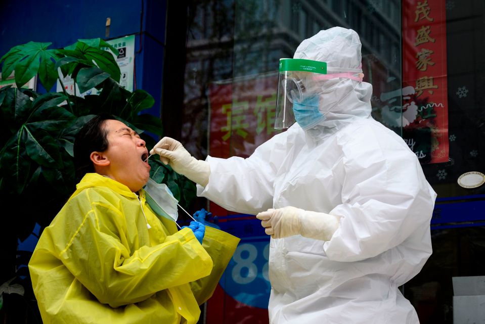  A medical worker wearing a hazmat suit swabs a woman to check if she has coronavirus in Wuhan, China's central Hubei province on March 28