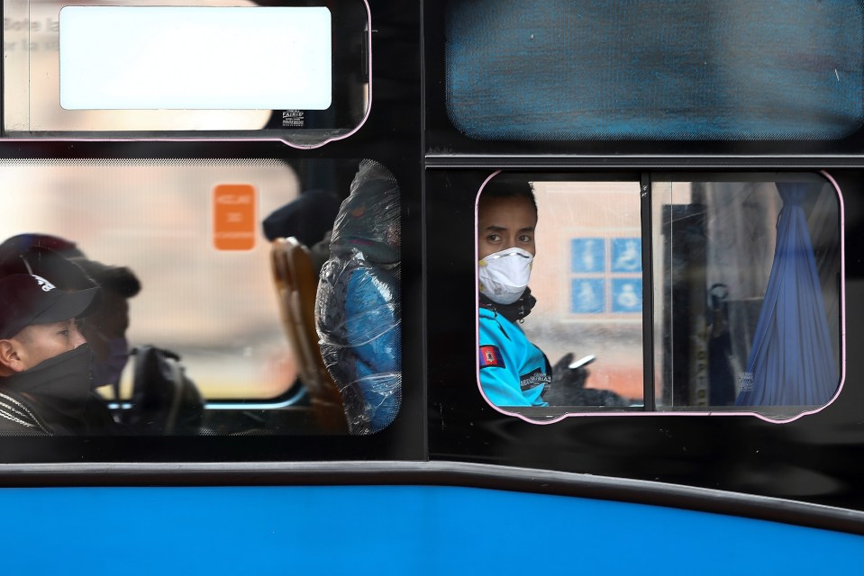  People cover their faces as they use public buses, in downtown Quito, Ecuador