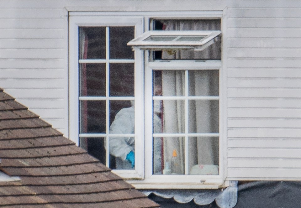  A forensics officer works by a window inside the property