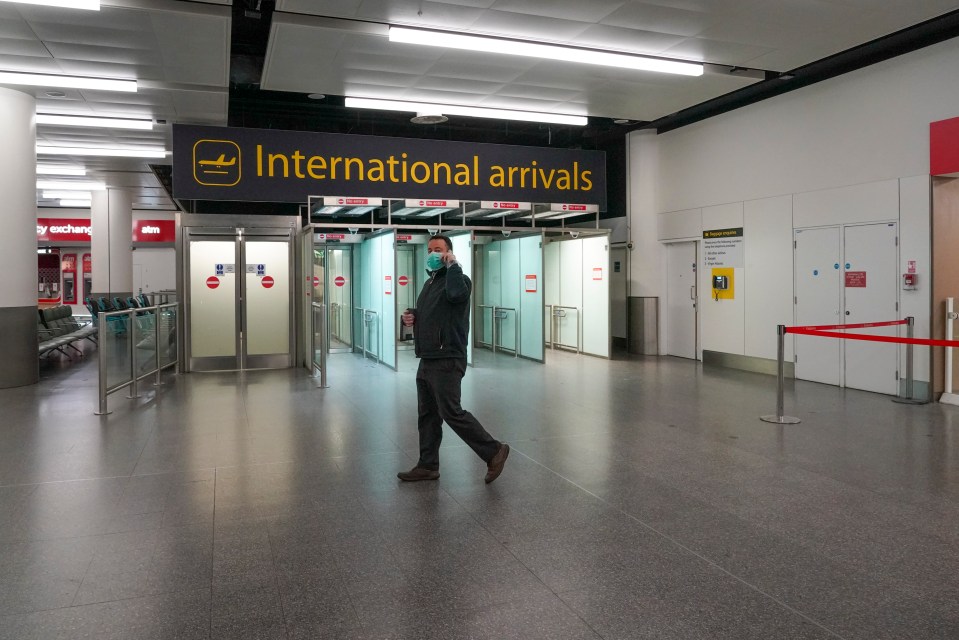 A masked worker walks through a deserted Gatwick Airport