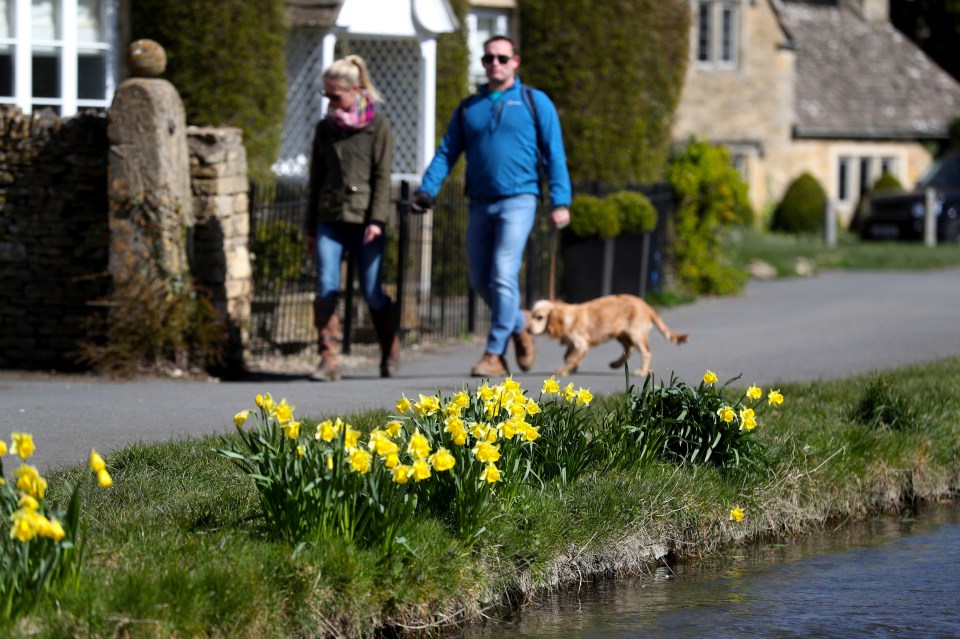 Dog walkers in the village of Lower Slaughter in the Cotswolds, Gloucestershire