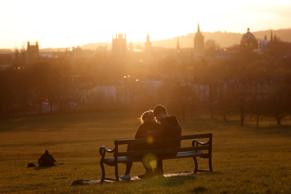 A couple is seen on a bench at sunset in Oxford as the spread of the coronavirus disease