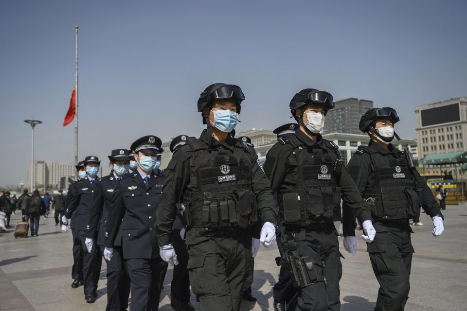  Chinese police officers wear protective masks as they march in formation during the tribute to coronavirus victims on April 4