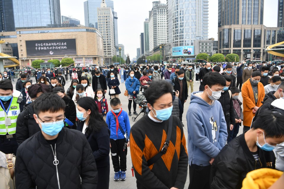 People stand in silent tribute at a square during a three minute national memorial to coronavirus victims on April 4