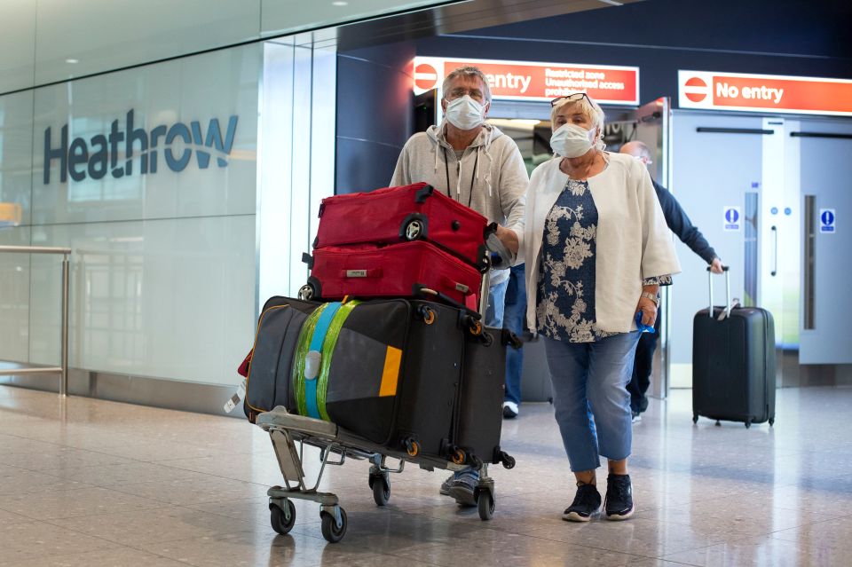  Passengers walk through Heathrow Airport wearing masks