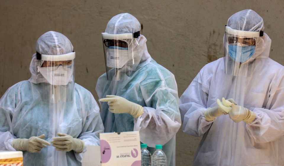  ndian medical staff prepare themselves with protective gear before collecting a swab sample on April 7