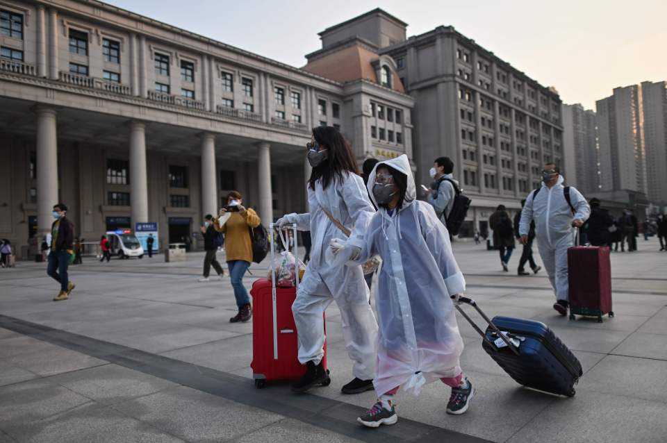  Travellers in protective clothing arrive for an early morning train at Wuhan station