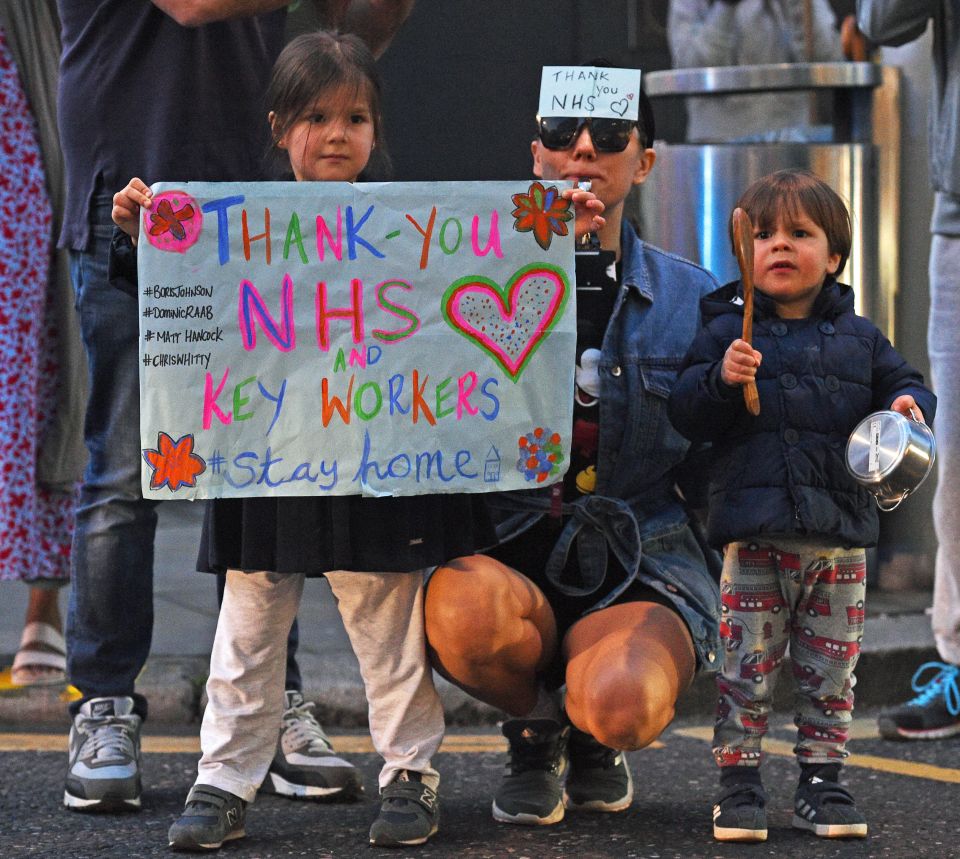  A family, including a child with a saucepan, stand outside the Chelsea and Westminster Hospital