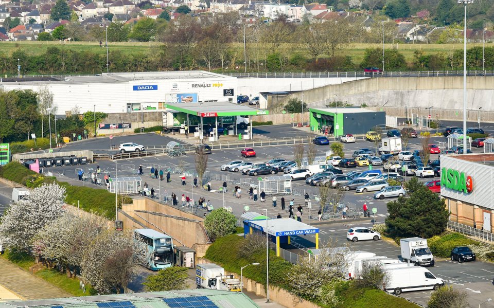  Shoppers at an Asda supermarket in Hollingbury, Brighton have been pictured queuing through the car park this morning