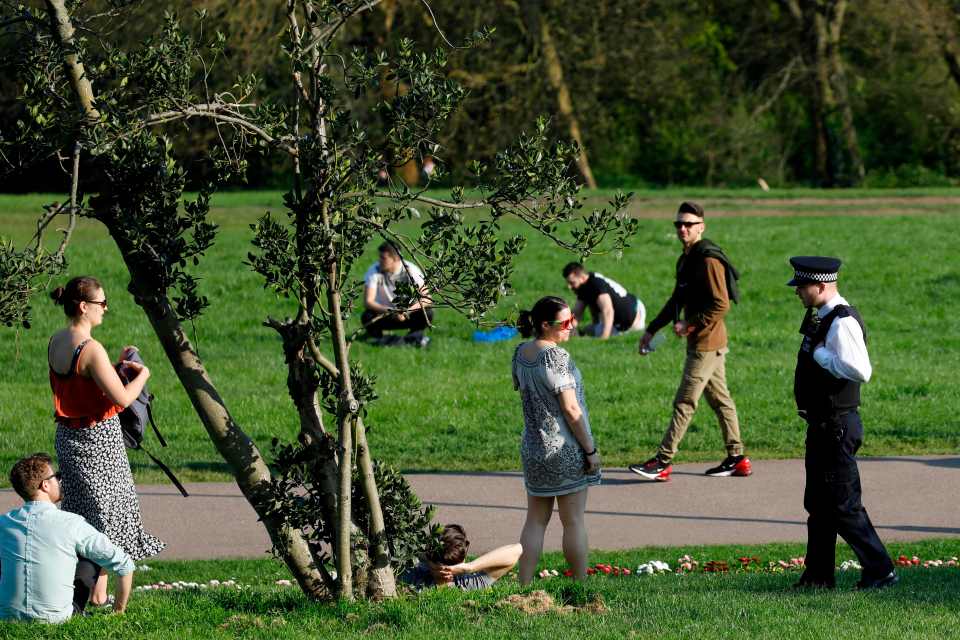  A police officer speaks to people in Alexandra Park in north London as people enjoy the sun on Good Friday