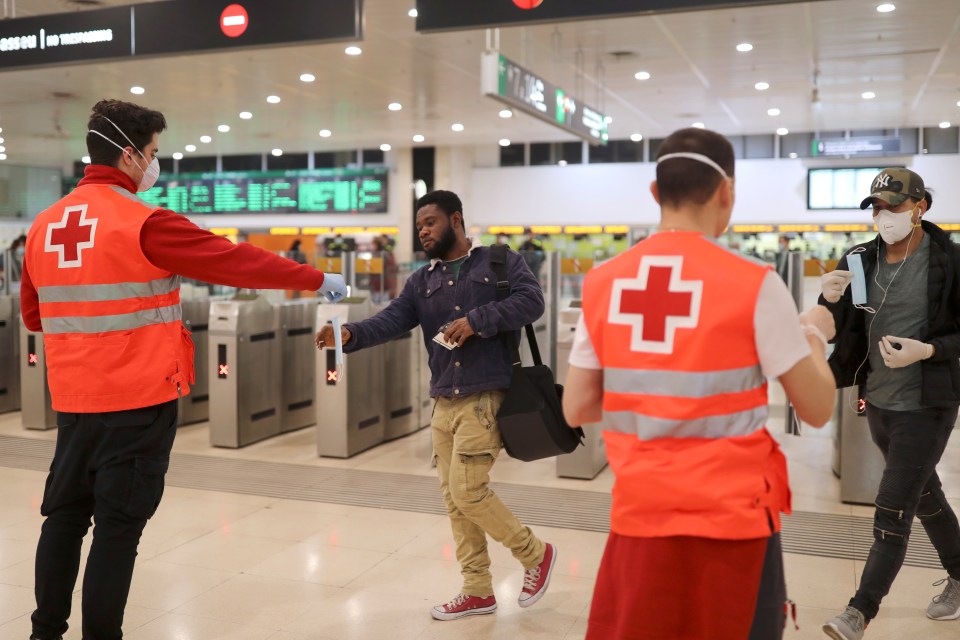 Volunteers hand out face masks to commuters in Barcelona today as some non-essential workers were allowed back to work