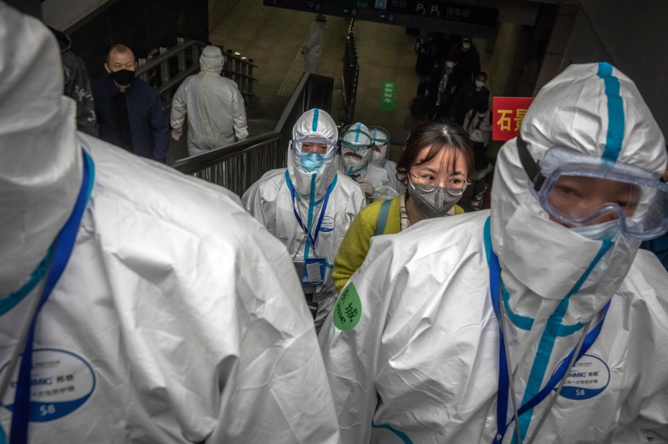  Passengers arriving from Wuhan ride a moving staircase together with railway workers wearing full protective gear to board dedicated buses, at the railway station in Beijing