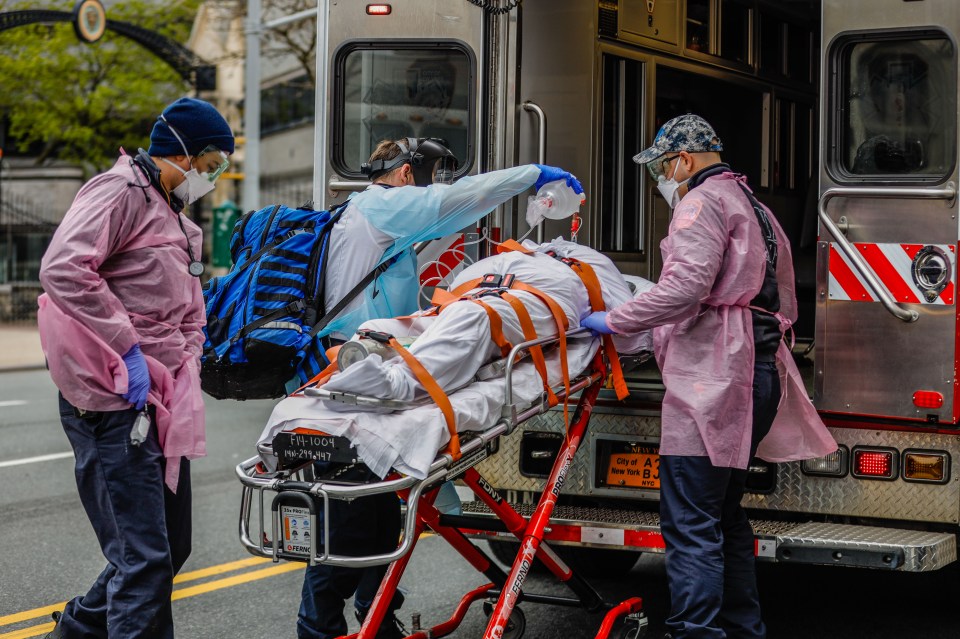  New York health professionals transport a man using a mechanical respirator and oxygen cylinder on Apirl 20