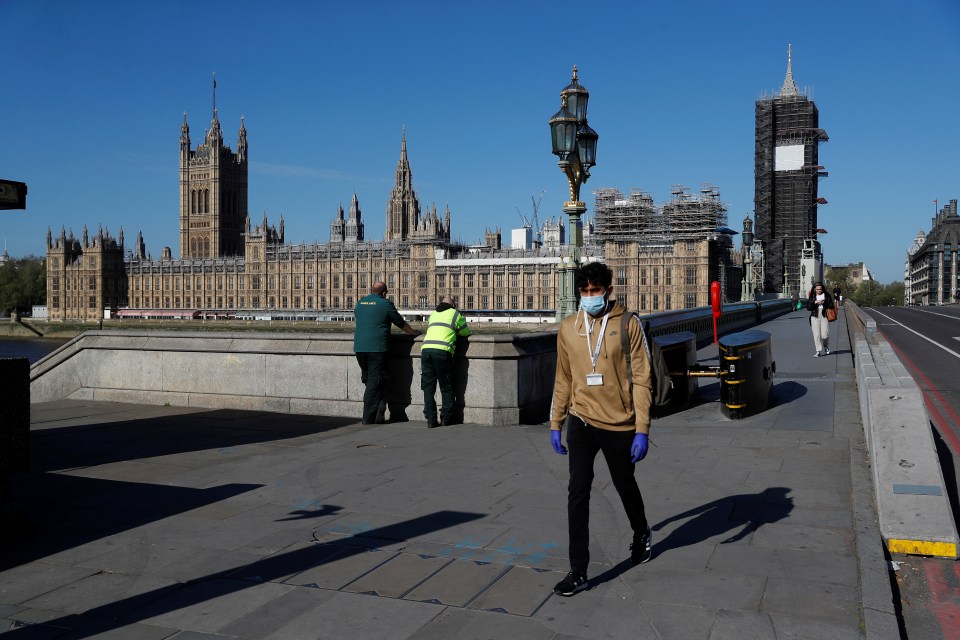 A man in a mask walks across Westminster Bridge today