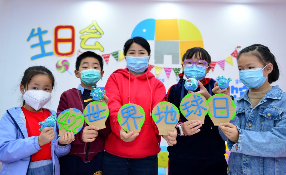 Students and their teacher in China show off their clay work to mark Earth Day