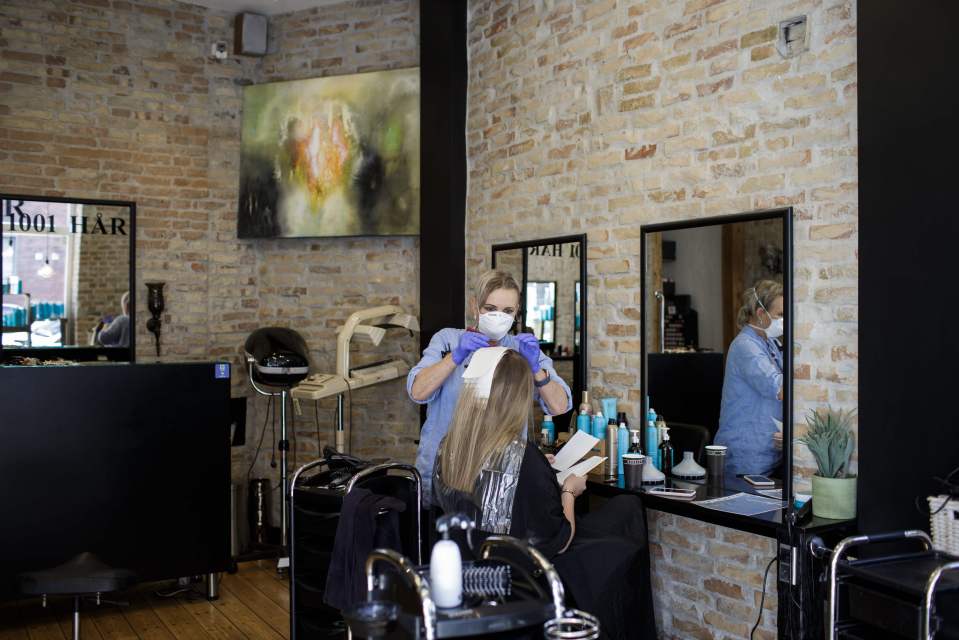 A hairdresser wears a face mask and gloves after salons were able to reopen in Copehagen 