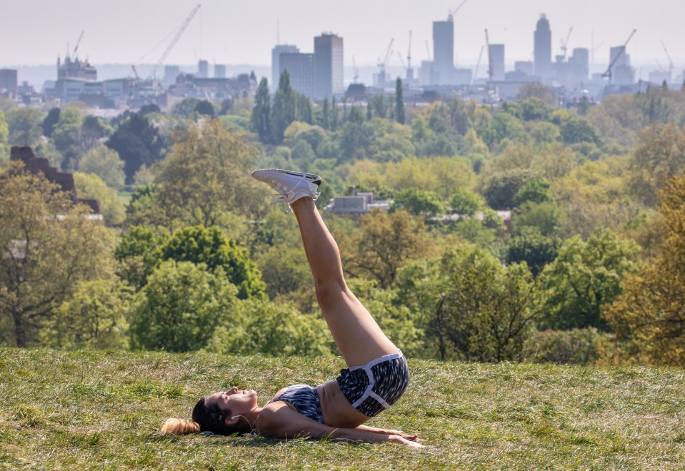  A woman exercises on Primrose Hill in London today