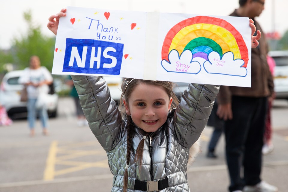 A girl holds up a sign outside Whiston hospital in Merseyside for the fifth Clap For Carers