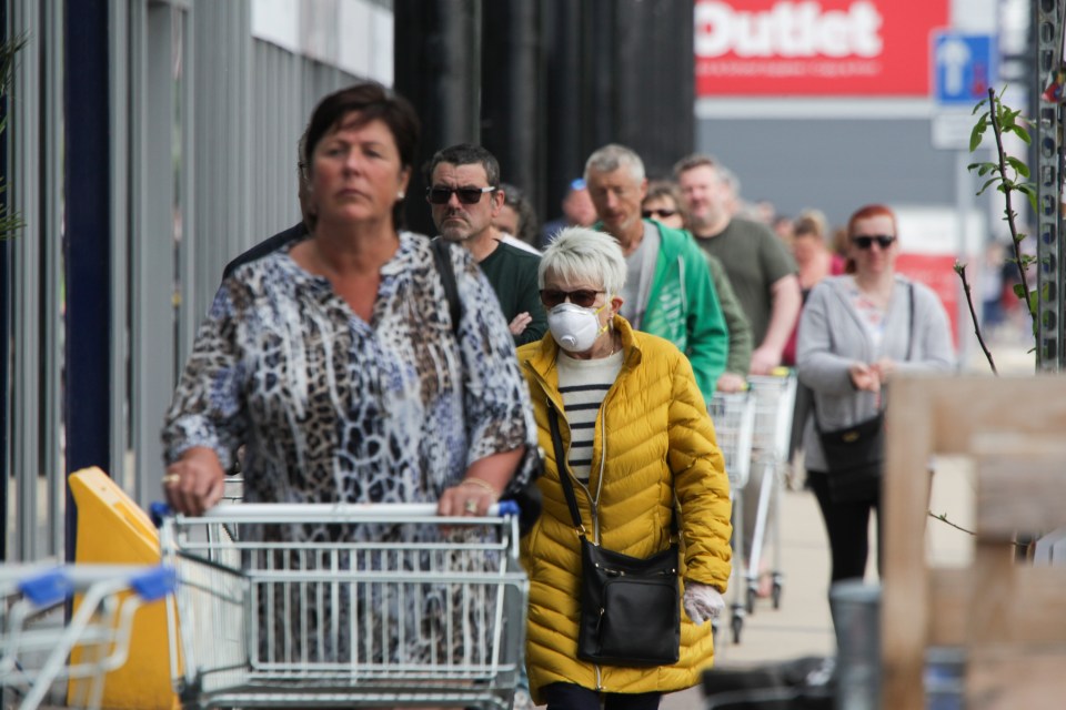  A woman wears a face mask in the queue for The Range in Derby today