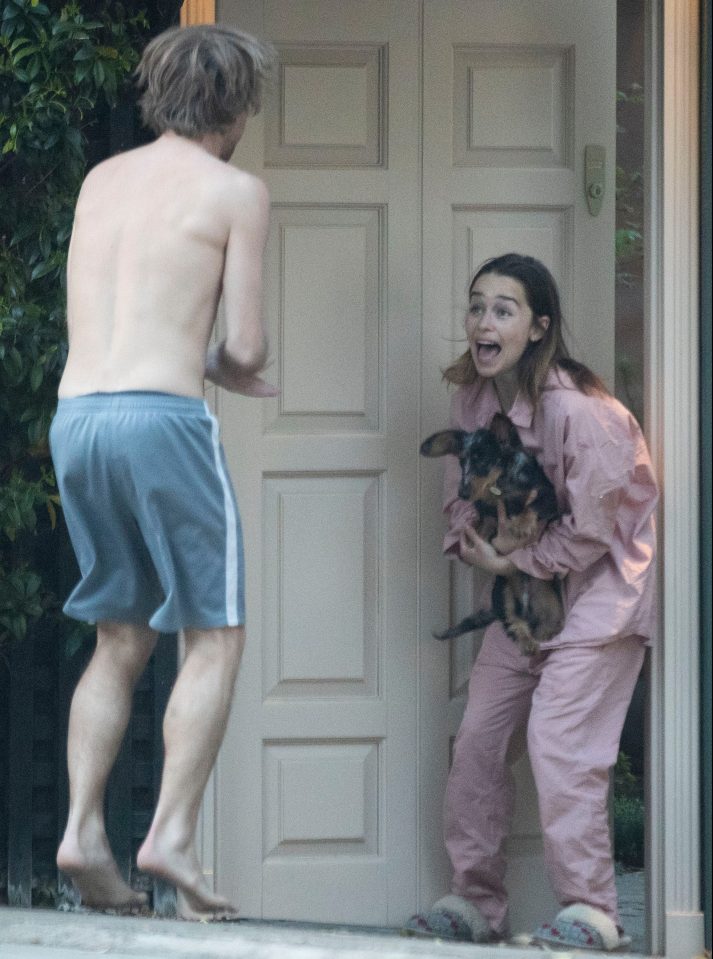 The actress looked on in pyjamas while cradling her dog as her topless friend bounced around