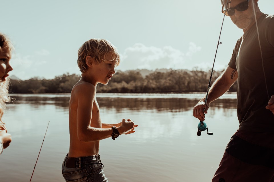  Father enjoys a day out fishing on the river with his kids in Australia