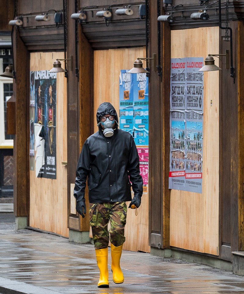  Man in a gas mask walks past closed shops in London on April 28