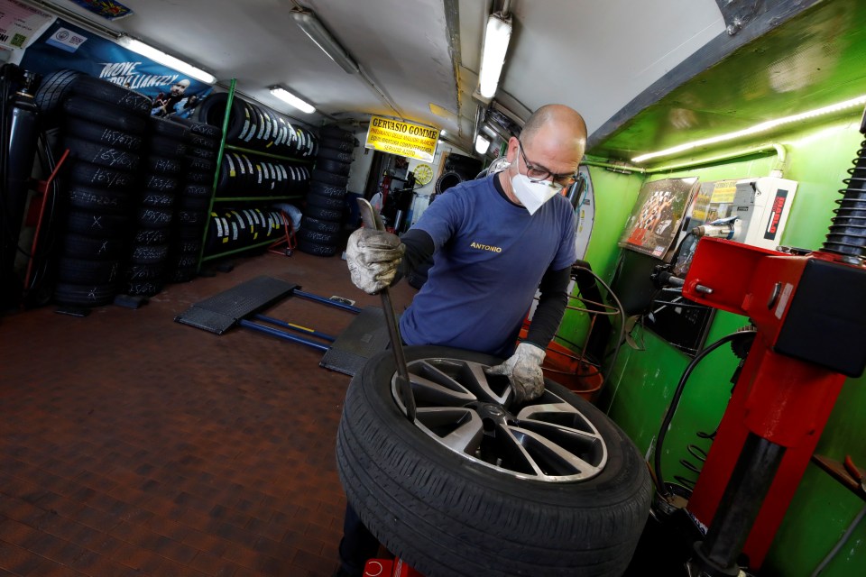  A tire service employee works on a wheel in a workshop open again after lockdown restrictions were eased