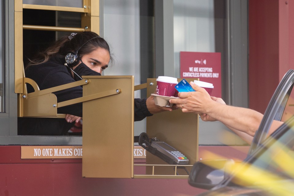 This barista in Croydon, South London wore a face mask for protection as she served a customer