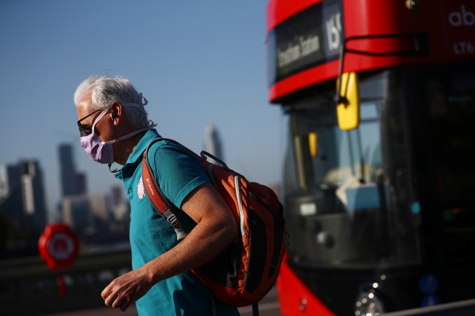  A man wearing a mask walks over Westminster Bridge in London