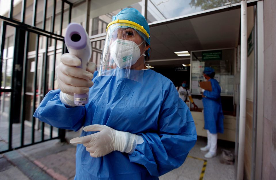  A health worker wearing PPE measures the temperature of people outside of the IMSS General Hospital in Mexico City