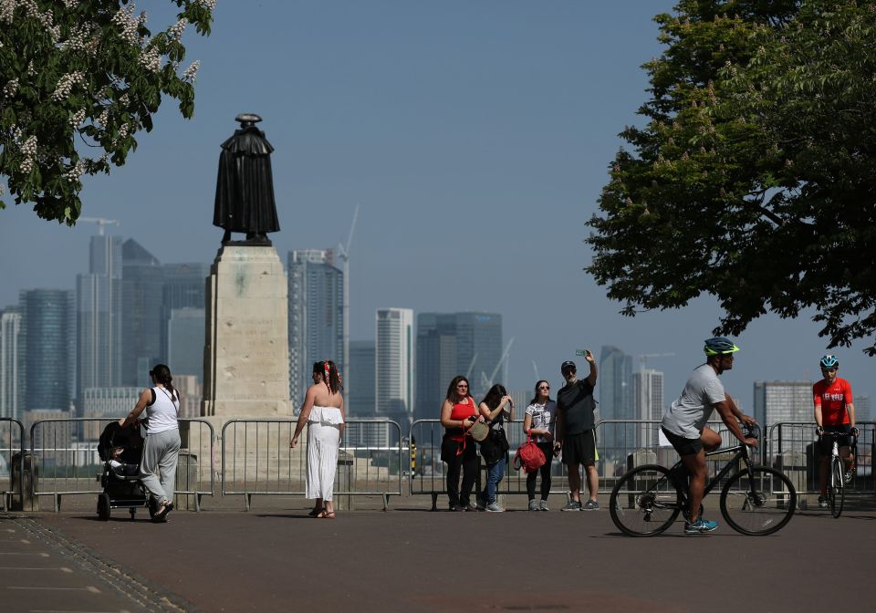  People are seen  basking in the sun at Greenwich Park