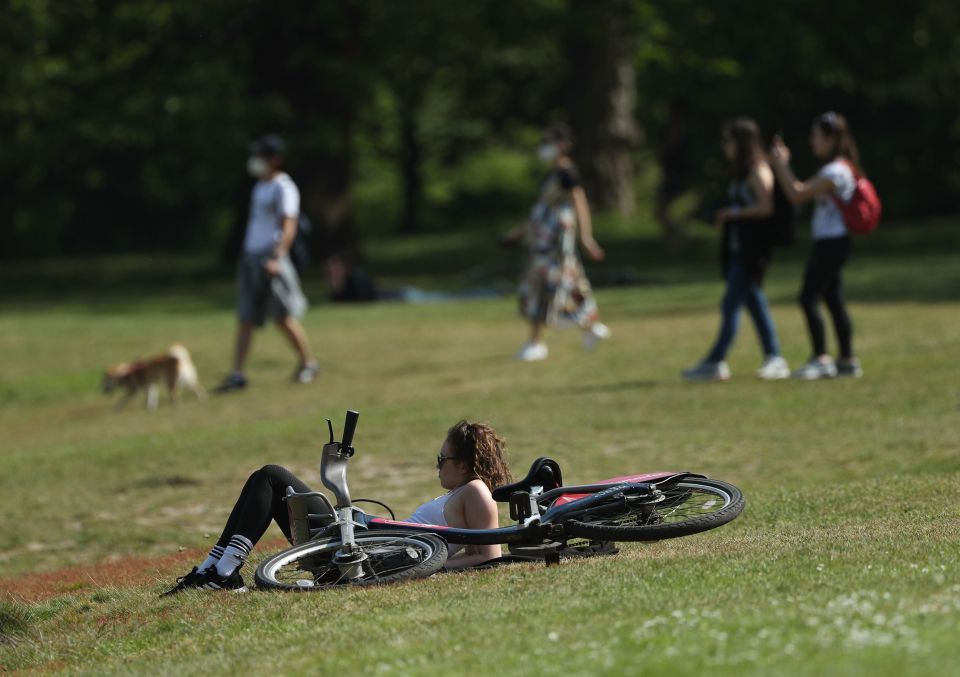  A cyclist takes a break and sits on the grass at Greenwich Park