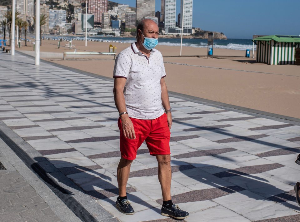  A man wearing a protective face mask walks along the promenade in Benidorm on May 11