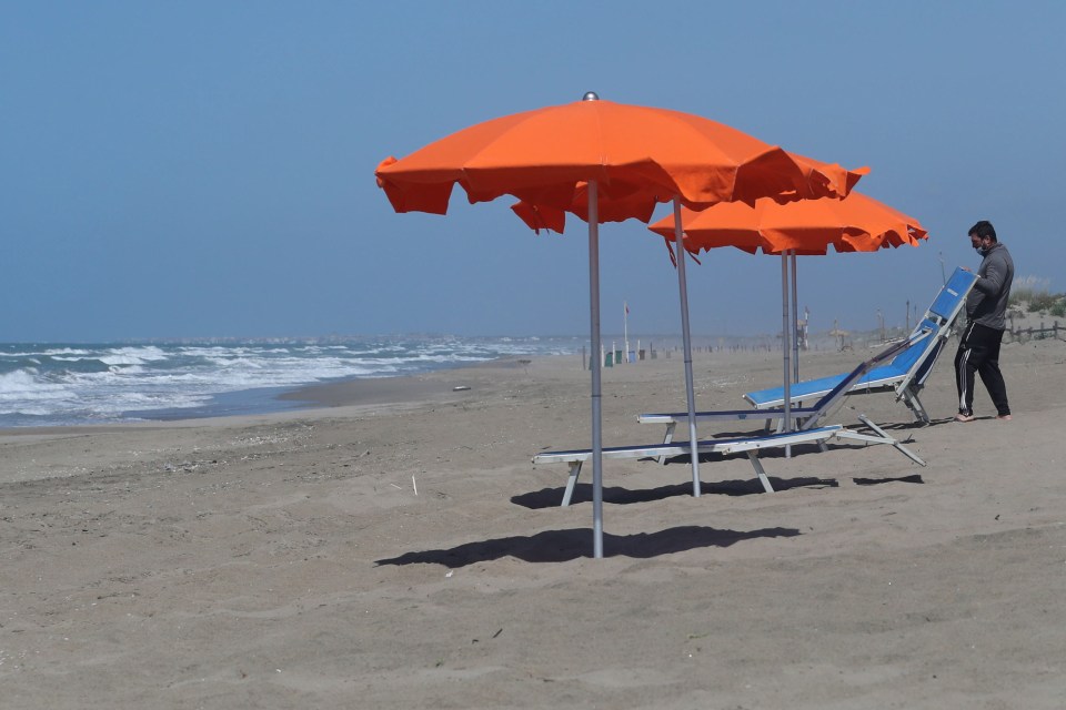  A worker sets up deck chairs and parasols on the beach of Capocotta, near Rome on May 12