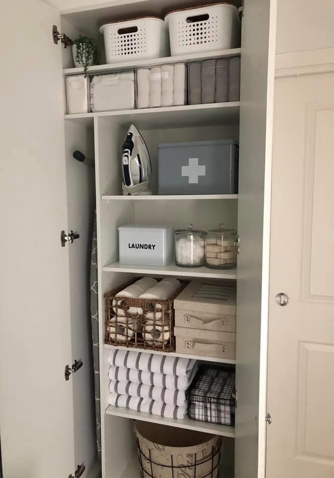 The laundry cupboard houses extra toilet rolls and supplies in containers