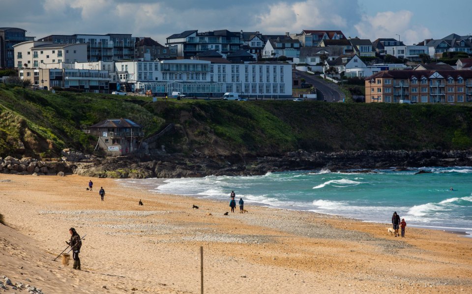 Walkers take a stroll at the Fistral beach in Newquay, Cornwall