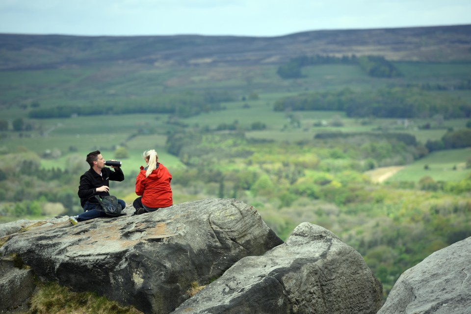 A couple pause during a walk on the Cow and Calf Rocks on Ilkley Moor above Ilkley, West Yorkshire