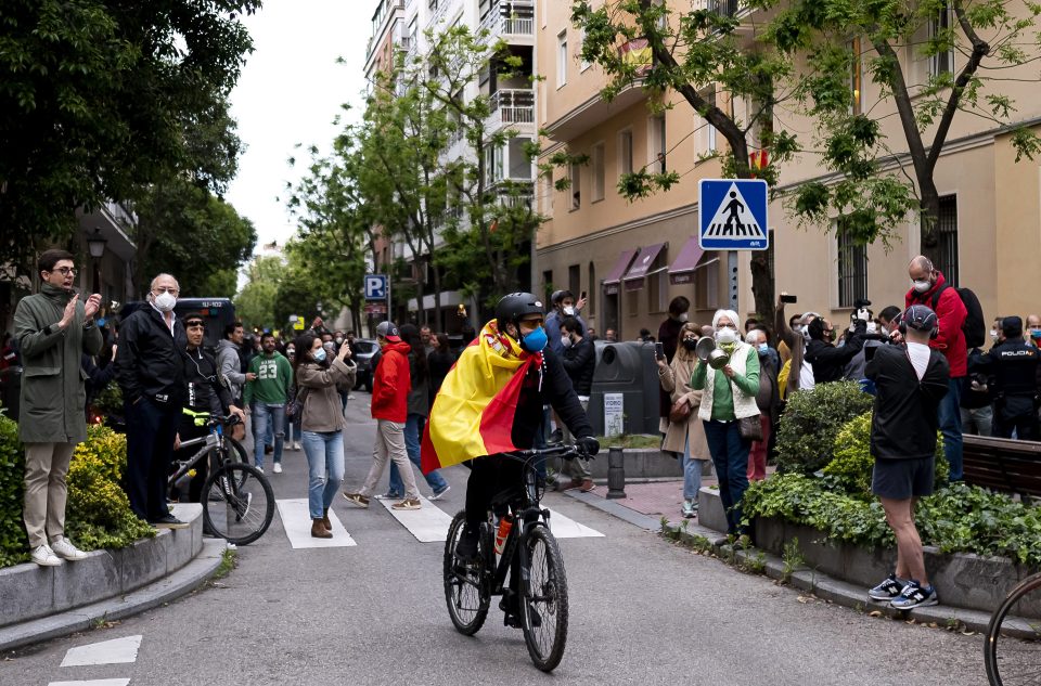  A man rides a bike through a protest in Madrid