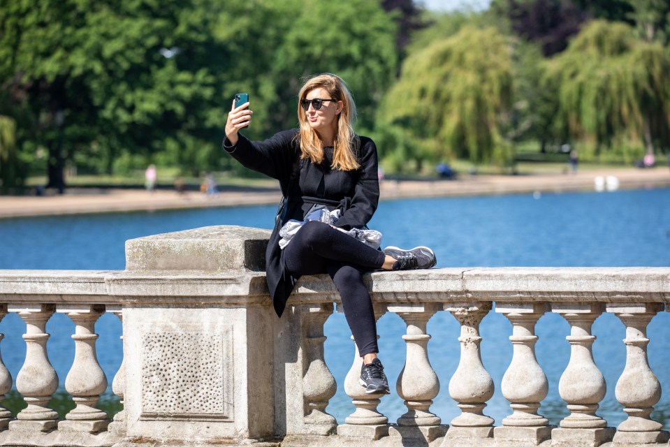  A women takes a selfie while enjoying the sunshine in Hyde Park as weather experts predict a very warm week ahead