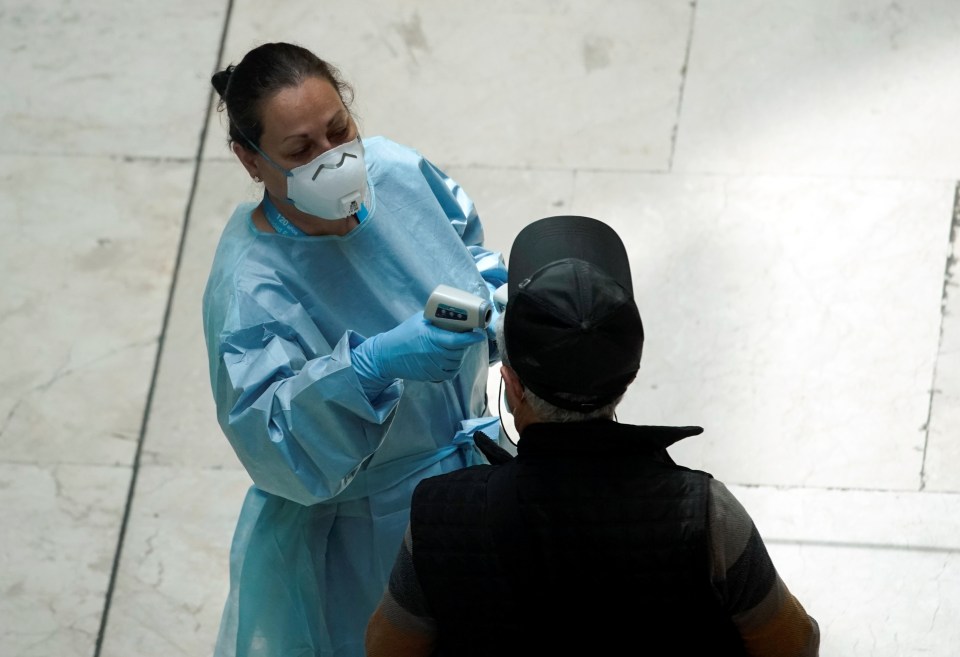  A healthcare worker takes a passenger's temperature at the Adolfo Suarez Barajas Airport in Spain on May 15